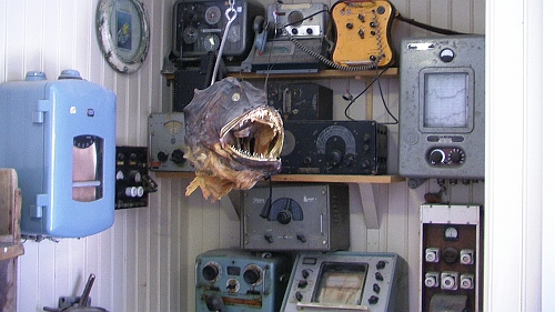 PIC_1184.JPG - Vorher schauen wir noch beim Restaurant vorbei. Hier gibts eine kleine Ausstellung alter Funkgeraete die von einem Fischkopf bewacht werden. Oder war das der alte Funker .....?