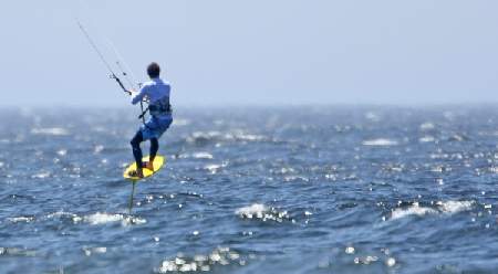 kiter.jpg - Und dann trauen wir unseren Augen kaum, als ein Kiter mit seinem Brett ueber das Wasser fliegt. Erst beim Naeherkommen sieht man, dass da unter dem Brett noch irgendwas ist...