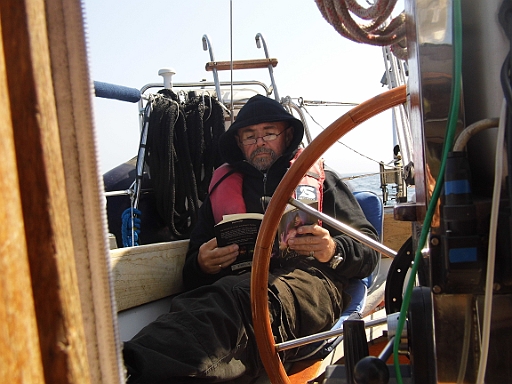 DSCI0367.JPG - Die Ueberfahrt nach Roedvig ist eher entspannt. Der Autopilot steuert, und so hat der Skipper endlich nach langer Pause wieder einmal Zeit zum Lesen.