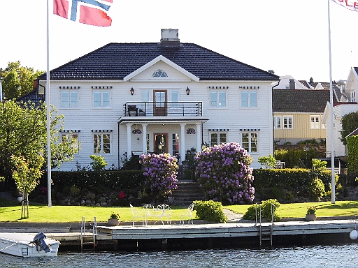 DSCI0978.JPG - Wir verlassen das gastliche Lillesand mit Ziel Blindleia. Das Wetter soll die beiden naechsten Tage endlich,  mal richtig schoen werden und wir wollen den Ankerplatz des letzten Jahres aufsuchen. Hoffentlich ist der noch frei... Beim Auslaufen gefaellt der Bordfee dieses bescheidene Anwesen besonders gut....