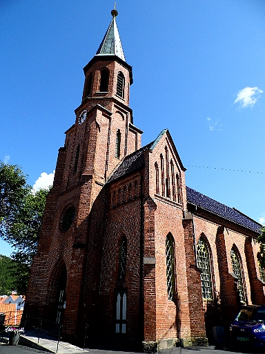 DSCI0577.JPG - Die Kirche von Tvedestrand. Wie in dieser Gegend ueblich, steht sie am hoechsten Punkt, was bedeutet, dass man erst mal maechtig steile Wege laufen muss, um sie zu erreichen. Eigentlich scheint sie geschlossen zu sein. Aber man kann ja mal an der Tuer ziehen. Und siehe da, wir sind drin. Zwar ist der Schlossriegel zu, aber die Verriegelung oben und unten wurde vergessen. Gut fuer uns, so war der Aufstig doch nicht umsonst.