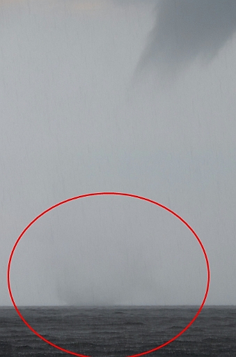 wasserhose.jpg - Auf dem Weg von Dragoer nach Roedvig wird es immer dunkler, dann "Schuetteregen". Wir nehmen erst die Genua weg, als es anfaengt zu Blitzen und zu Krachen. Dann, als wir diesen sich entwickelnden Twister shen, auch noch blitzschnell das Grosssegel. Im Kreis kann man erkennen, dass er schon anfaengt Wasser aufzusaugen,obwohl er noch nicht ganz unten angekommen ist.